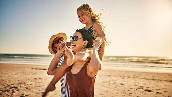 Young couple at the beach with child on ladies shoulders