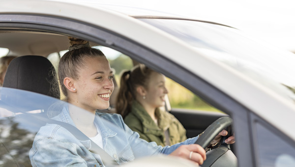 Two people sitting in front seats of a car, driver on the left.